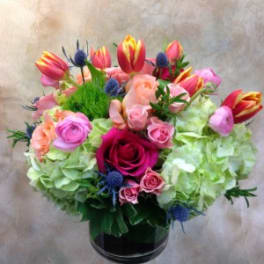 Mixed bouquet of roses, tulips, and hydrangeas in a glass vase