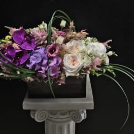 Mixed floral arrangement with purple orchids and white roses in a rectangular container