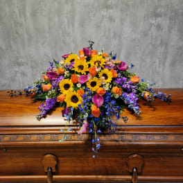 Colorful floral spray with sunflowers, roses, calla lilies, and purple blooms