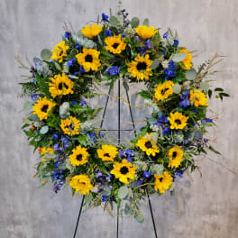Sunflower wreath with blue flowers on a black easel