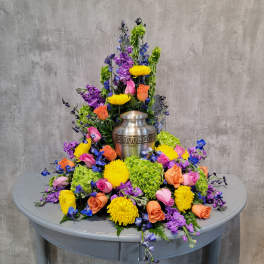 Colorful floral arrangement surrounding a silver urn on a table