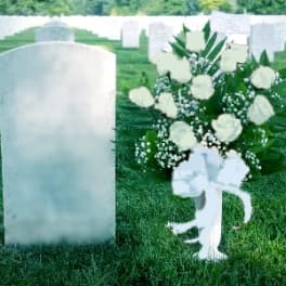 White floral spray beside a gravestone in a cemetery