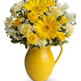 Yellow and white flower bouquet in a yellow pitcher vase