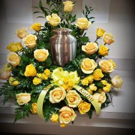 Yellow roses arranged around a memorial urn with a ribbon