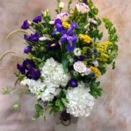 Tall bouquet of purple, white, and yellow flowers in a vase