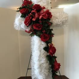 Standing cross covered with red roses and white ruffled flowers
