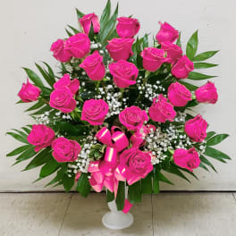Bright pink roses in a white vase with baby's breath and greenery