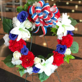Floral wreath with red, white, and blue flowers and a patriotic ribbon bow