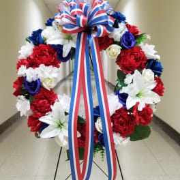 Red, white, and blue floral wreath with a striped ribbon bow