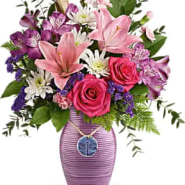 Pink lilies, roses, and purple flowers in a lavender vase