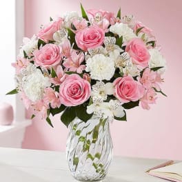 Pink roses and white flowers arranged in a clear glass vase
