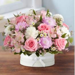 Pink and white mixed flower arrangement in a round white box