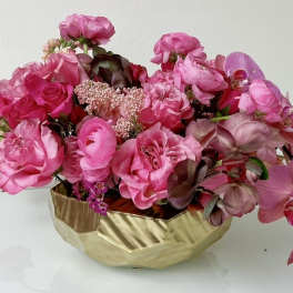 Pink floral arrangement in a gold bowl vase