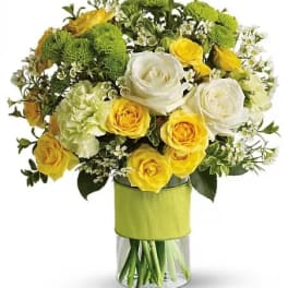 Yellow and white roses in a glass vase with green mums