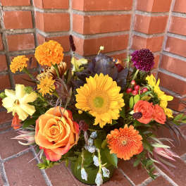 Mixed bouquet with sunflowers, roses, and chrysanthemums in a green vase