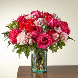 Pink roses and carnations arranged in a clear glass vase