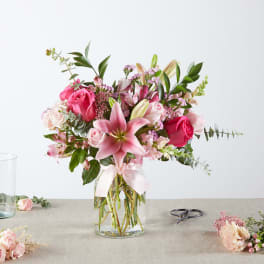 Pink and white bouquet with lilies and roses in a clear glass vase
