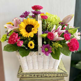 Mixed flowers in a white basket with a handle