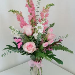 Pink and white floral arrangement in a glass vase with a butterfly accent