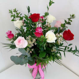 Mixed roses in a glass vase with a pink ribbon