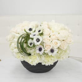 White rose and anemone arrangement in a black bowl vase
