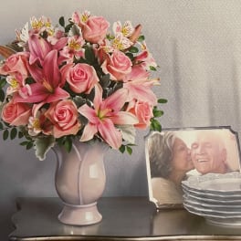 Pink roses and lilies arranged in a pale vase on a table
