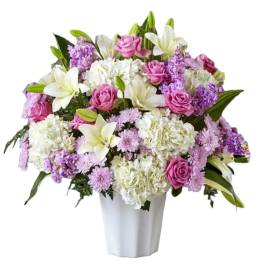 Pink roses and white lilies arranged in a white vase
