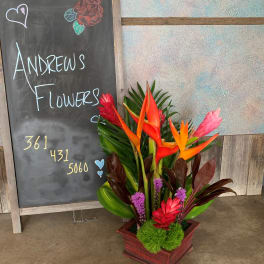 Tropical flower arrangement in a wooden box with orange and pink blooms