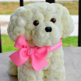 White flower-covered dog figure with a pink bow