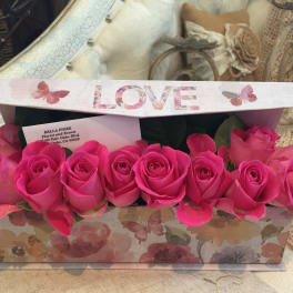 Pink roses arranged in a floral gift box with a LOVE lid