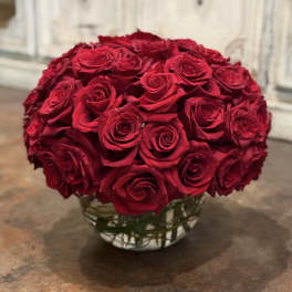 Round bouquet of red roses in a clear glass vase