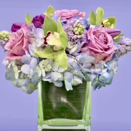 Pink roses and blue hydrangeas arranged in a clear glass vase