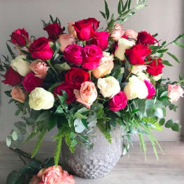 Large bouquet of red, pink, and cream roses in a silver vase