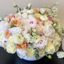 Large pastel bouquet of roses and ranunculus in a white basket