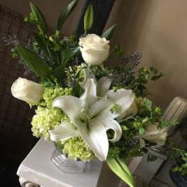 White lilies and roses arranged in a glass vase