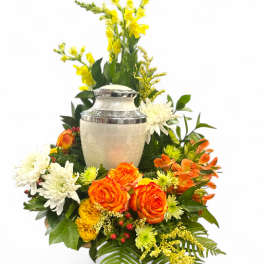 Floral arrangement with orange and white blooms around a silver urn