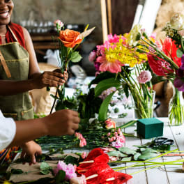 People arranging colorful flowers on a table in a workshop