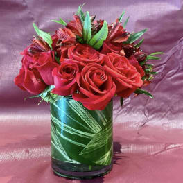 Red roses arranged in a green glass vase