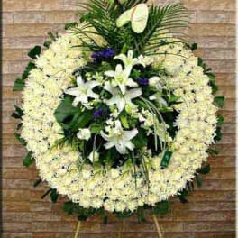 Large standing floral wreath with white lilies and pale blooms on an easel