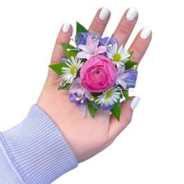 Pink floral corsage with white daisies on a hand