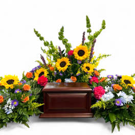 Casket surrounded by colorful funeral flowers with sunflowers and roses