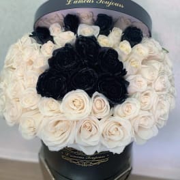 Black and white roses arranged in a round hat box