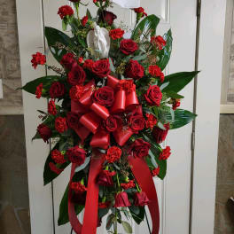 Standing spray of red roses and carnations with a red ribbon bow