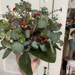 Handheld bouquet with eucalyptus, berries, and small purple accents