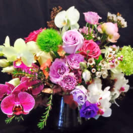 Mixed bouquet of pink, purple, white, and green flowers in a vase