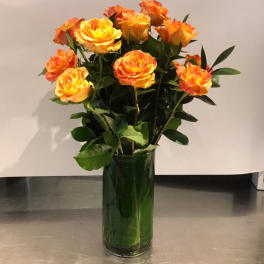Orange-yellow roses in a tall green glass vase