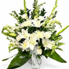 White lilies and spider mums in a vase with green foliage