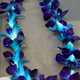 Blue and purple orchid lei on a gray surface