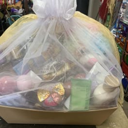 Gift basket wrapped in sheer tulle with assorted treats and candles