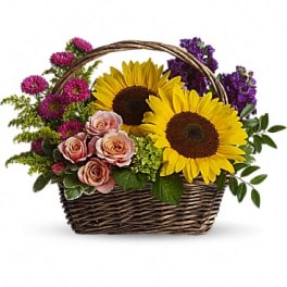 Basket arrangement with sunflowers, pink roses, and purple flowers
